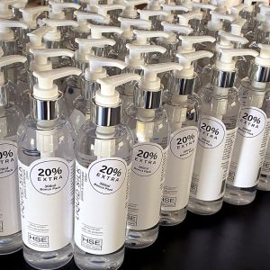 A row of bottles of HSE Liquid Silk Hair Polish Serum sitting on a table.