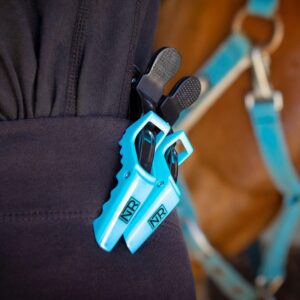 Two light blue NTR Mane Sectioning Clips clipped to the pocket of black pants.