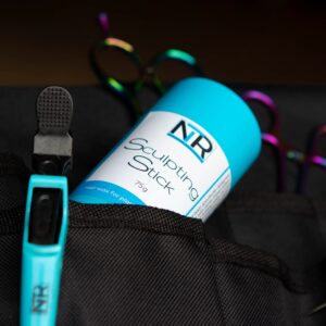 Image of a blue NR Sculpting Stick, labeled 75g, positioned in a black fabric holder. Adjacent are colorful, multi-colored scissors and a blue tool with a textured black tip.