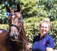 A woman in a blue shirt standing next to a brown horse.