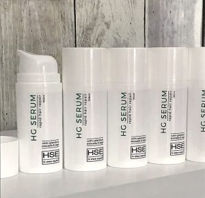 Five bottles of HSE HG Serum - Rapid Hair Repair sitting on a shelf.