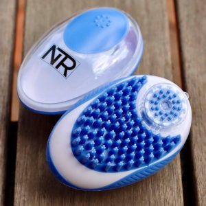Two blue and white NTR Shampoo Brushes on top of a wooden table.